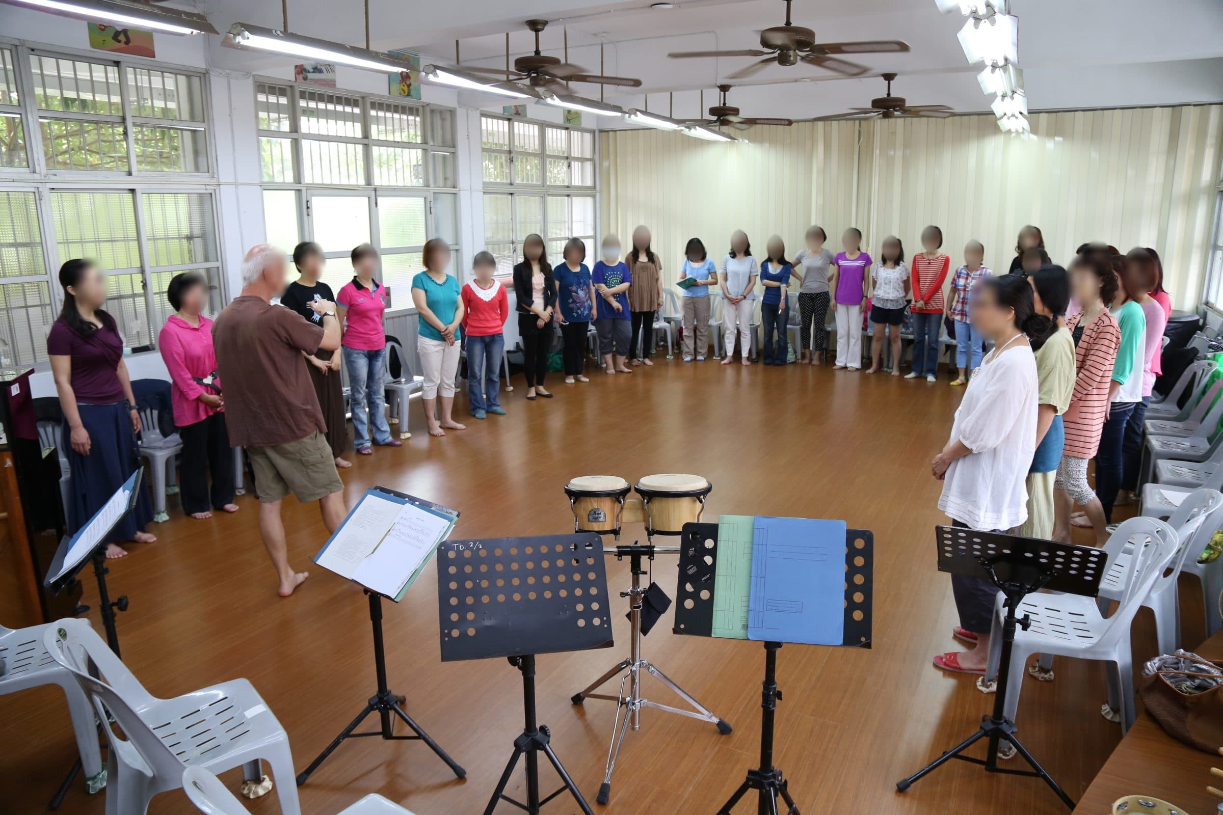 Workshop group standing in a wide circle around congas and music stands