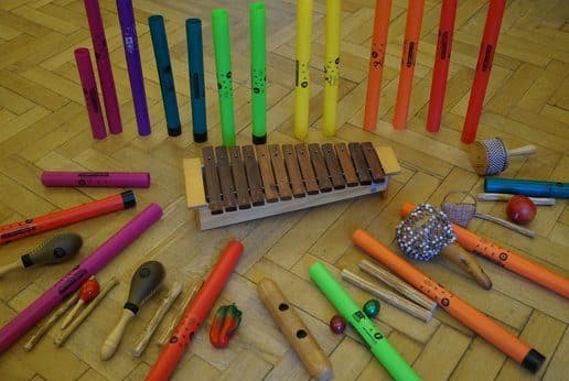 Boomwhackers, xylophone, maracas, shakers and claves laid out on a wooden floor