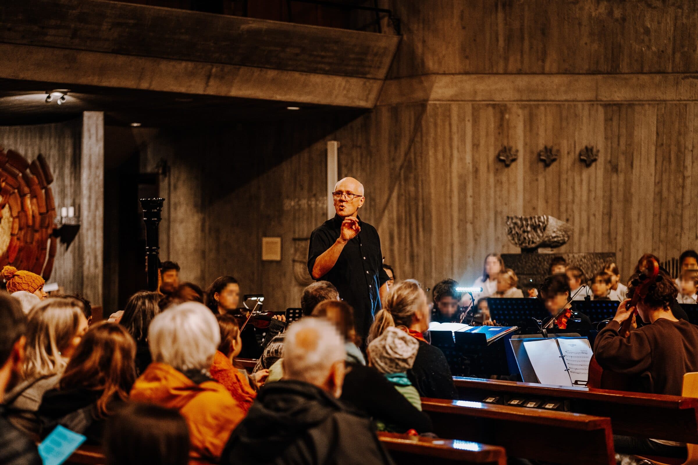 Markus Weiss speaking to the audience at a concert in front of the orchestra